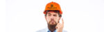 Quizzical man pointing at his hard hat
